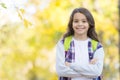 Teen girl carry backpack on the way to school. child walk in autumn forest. fall leaves in park. seasonal weather Royalty Free Stock Photo