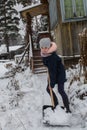 Teen girl cleans snow near a rural house. Winter. Royalty Free Stock Photo