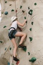 A teen girl climbing on a rock wall.