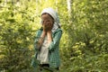 Teen girl closes her face by arms crying in the green dense forest in summer time Lost in woods, rescuer, lifesaver concept.