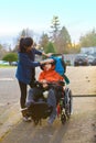 Teen girl comforting sad disabled little boy in wheelchair outdoors Royalty Free Stock Photo