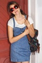 Teen girl in denim leans against red door. Royalty Free Stock Photo