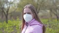 Teen girl dresses a mask on the street in spring.