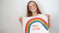 Teen girl drew rainbow and poster stay home.