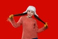 Teen girl in earflap hat of winter fashion style and knitted warm sweater with mittens isolated on red