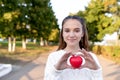 Teen girl Emotions joy smile and happiness, summer park, red toy heart hands. Free space copy text. Concept donation