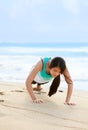 Teen girl exercising on beach near blue ocean waters Royalty Free Stock Photo