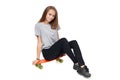 Teen girl in full length sitting on skate board Royalty Free Stock Photo