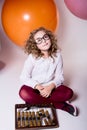 Teen girl in glasses with wooden abacus on the background of large rubber balls. Royalty Free Stock Photo