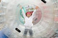 Teen girl happily runs inside a large inflatable cylinder-zorb
