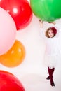 Teen girl in a hat and white dress on a background of big colored rubber air balls Royalty Free Stock Photo