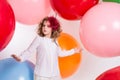 Teen girl in a hat and white dress on a background of big colored rubber air balls Royalty Free Stock Photo