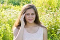 Teen girl with a headache on a blossoming meadow