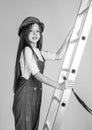 teen girl in helmet and boilersuit on stepladder. child on ladder wear hard hat. kid builder on construction site