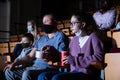 Teen girl with father in protective masks watching movie in cinema