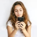 Teen girl holding a black phone in her hands and looking at the screen Royalty Free Stock Photo