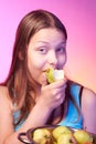Teen girl holding a colander full of apples and eating an apple