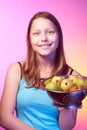 Teen girl holding a colander full of apples