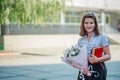 Teen girl holds a bouquet of flowers and goes to school.