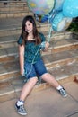 Teen girl holds bunch of balloons