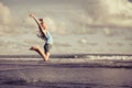 Teen girl jumping on the beach at blue sea shore Royalty Free Stock Photo