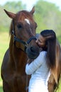 A teen girl kisses her horse in a beautiful field. Royalty Free Stock Photo