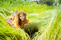 Teen girl learns working on laptop lying on meadow. mobile Internet in rural