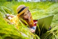 Teen girl learns working on laptop lying on meadow. mobile Internet in rural