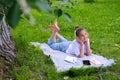 Teen girl lies listens to music in headphones on the grass in the park with books and notebooks Royalty Free Stock Photo