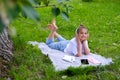 Teen girl lies listens to music in headphones on the grass in the park with books and notebooks Royalty Free Stock Photo