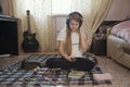 Teen girl listening to music in headphones using smartphone sitting on the floor at home Royalty Free Stock Photo