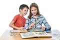 Teen girl and little boy with magnifier looking his stamp collection isolated Royalty Free Stock Photo