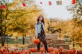 Teen girl with long hair posing with pumpkins at the open farm market place. Autumn background