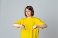 Teen girl in yellow casual tshirt looking displeased showing rejection and negative with thumbs down gesture, stand over light Royalty Free Stock Photo