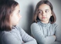 Teen girl looks at her reflection in the mirror. Royalty Free Stock Photo