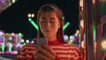 Teen girl making call in neon luna park closeup. Pretty girl resting amusement Royalty Free Stock Photo