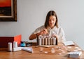 Teen girl making handmade advent calendar house from toilet paper rolls and carton box.