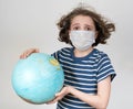 Teen girl in a medical mask holds the globe