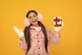 teen girl in mittens hold present on yellow background. xmas holiday gift. Royalty Free Stock Photo