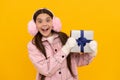teen girl in mittens hold present on yellow background. xmas holiday gift. Royalty Free Stock Photo