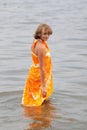 Teen girl in orange dress dabbles in water Royalty Free Stock Photo