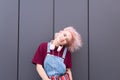 Teen girl with pink hair and stylish bright clothes smiles and poses on a dark background