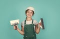 teen girl plasterer in protective helmet use spatula, plastering