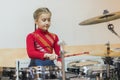 Teen girl playing the drums. Teen girls are having fun playing drum sets in music class. Girl in red drumming Royalty Free Stock Photo
