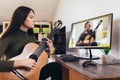 Girl playing guitar with computer, learn to play with an online course