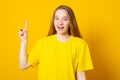 Teen girl points upwards with broad smile, recommends awesome product, suggests click banner, dressed casually Royalty Free Stock Photo