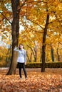Teen girl is posing near tree in autumn park. Beautiful landscape at fall season Royalty Free Stock Photo