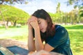 Teen girl praying outdoors at park table on sunny day Royalty Free Stock Photo