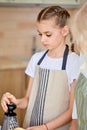 teen girl preparing food in kitchen, using grater, looking down