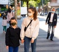 Teen girl and preteen boy in protective masks walking outdoors